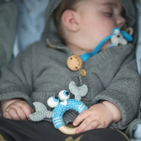 Gehäkelte Babyrassel Krabbe PINCER in Türkis mit schlafendem Baby