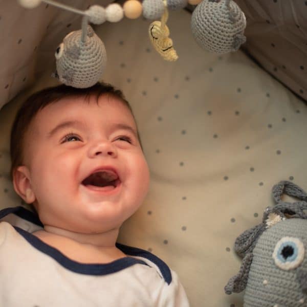 Gehäkelte Kinderwagenkette Eule LUNA in Grau mit lachendem Baby