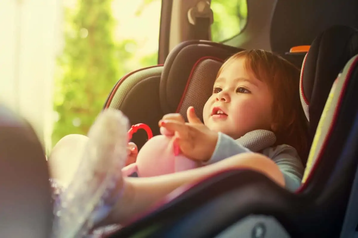 Baby mit Spielzeug im Kindersitz im Auto