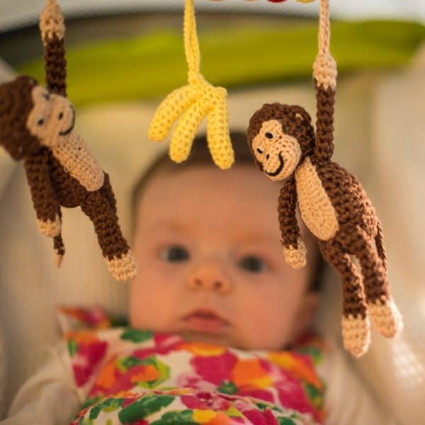 Gehäkelte Kinderwagenkette Affe CHARLIE in Braun - mit neugierigem Baby