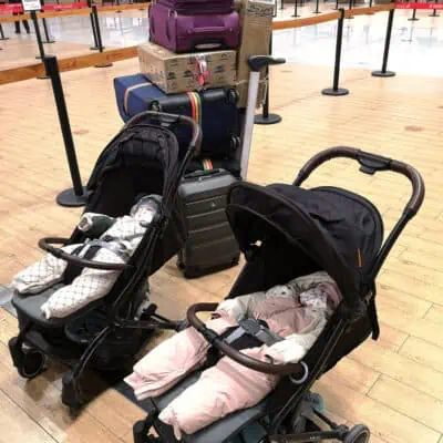 2 Babys im Kinderwagen am Flughafen-Check-In