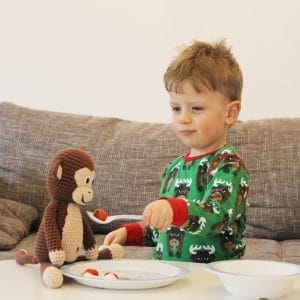 Häkelaffe mit Kleinkind beim Essen