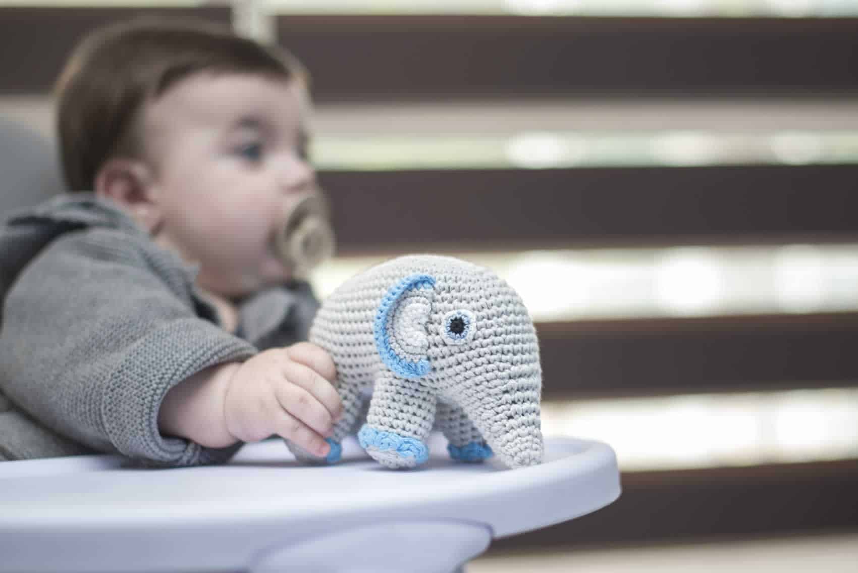 Baby mit Elefanten-Kuscheltier im Kindersitz (Kategorie-Bild)
