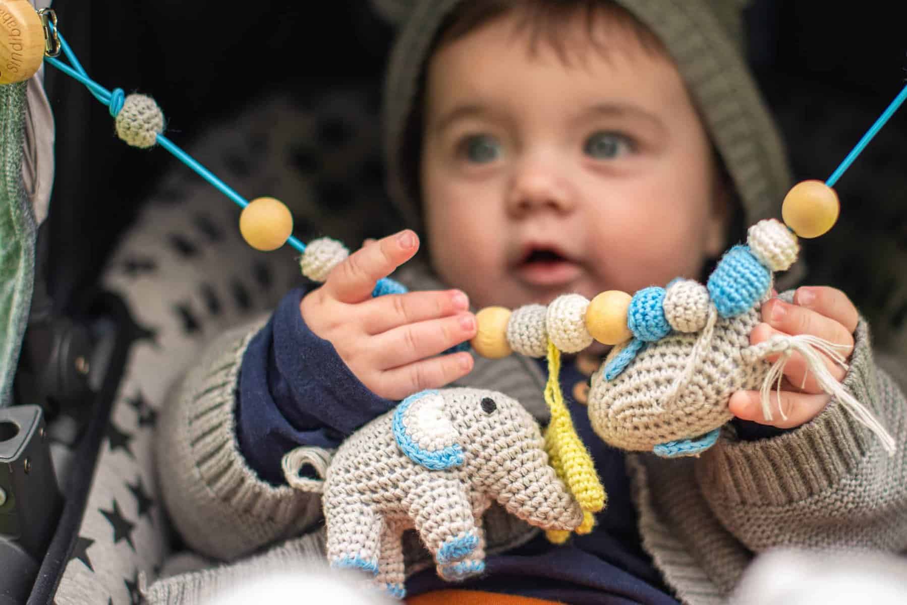 Babyspielzeug von SindiBaba - Baby-Junge mit Kinderwagenkette im Buggy