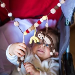 Gehäkelte Kinderwagenkette Affe CHARLIE in Braun - mit Baby beim Spielen